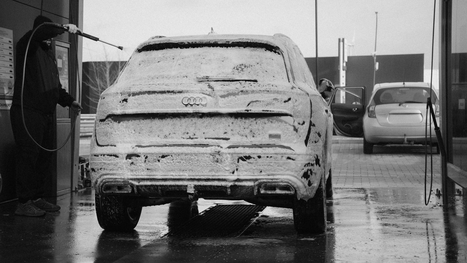 Glossy black sedan covered in foam during a hand wash