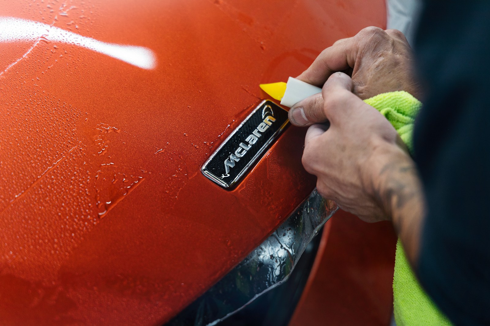 Hand polishing the side of a silver luxury car with a microfiber cloth